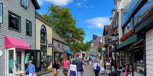 Visitors walking through Bannister’s Wharf lined with waterfront shops, restaurants, and coastal charm in Newport.