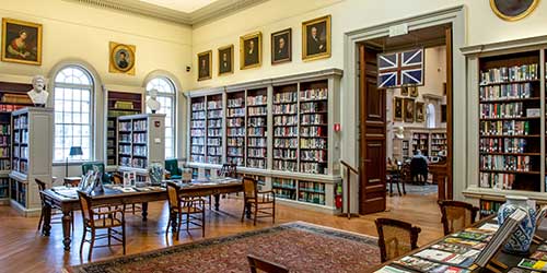 Historic reading room with bookshelves and portraits inside the Redwood Library & Athenaeum in Newport.