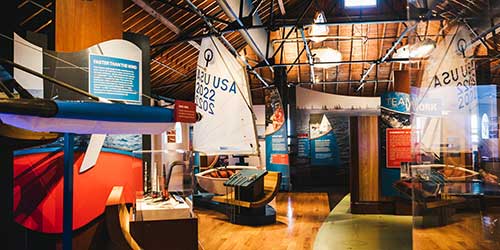 Interactive sailing exhibits and historic boats on display inside The Sailing Museum in Newport, Rhode Island.