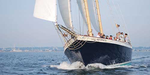 Sightseeing sailboat cruising along the Newport coastline with passengers enjoying an ocean tour.
