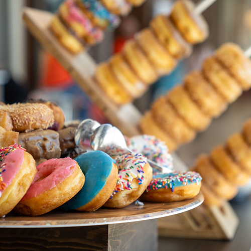 Plate of frosted donuts with stacks of glazed donuts in the background