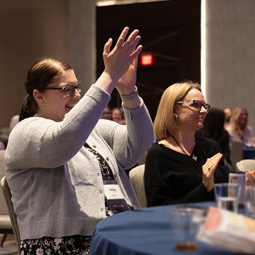 Attendees smiling and applauding during a session at DEAMcon26.